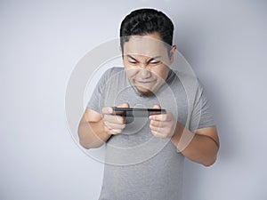 Funny Young Asian Guy Playing Games on Tablet