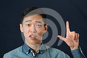 Funny young Asian man giving number two hand sign