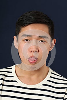 Funny young Asian man making face and showing his tongue