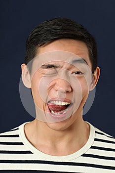 Funny young Asian man making face and showing tongue