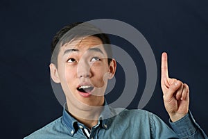 Funny young Asian man pointing his index finger upward