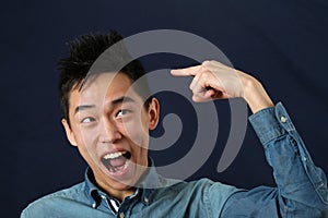 Funny young Asian man pointing the index finger at haircut