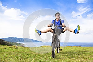 Funny young backpacker riding a bicycle on a meadow photo