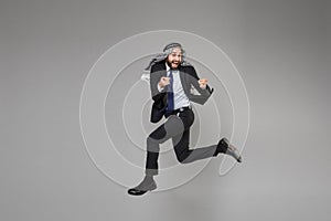 Funny young bearded arabian muslim businessman in keffiyeh kafiya ring igal agal suit  on gray background