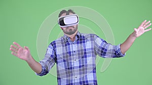 Funny young bearded hipster man using virtual reality headset and feeling nauseous