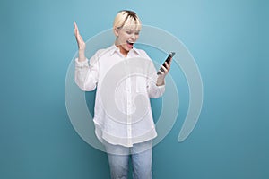 funny young blond business woman in a white shirt rejoices looking into a smartphone on the background with cop and