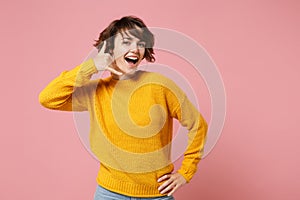 Funny young brunette woman girl in yellow sweater posing isolated on pastel pink background studio portrait. People