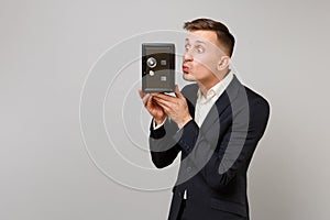 Funny young business man in suit blowing sending air kiss to metal bank safe for money accumulation in hand isolated on