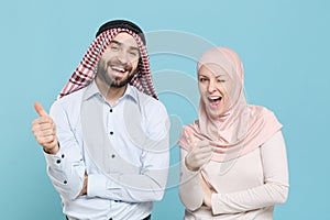 Funny young couple friends arabian muslim man wonam in keffiyeh kafiya ring igal agal hijab clothes isolated on blue