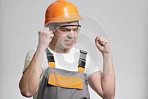 Funny young disgruntled foreman in hysterics on gray isolated background, comic emotions on his face
