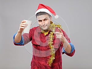 Funny young drunk man wearing Santa hat holding a paper cup