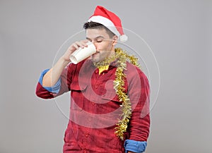 Funny young drunk man wearing Santa hat holding a paper cup