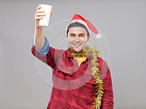 Funny young drunk man wearing Santa hat holding a paper cup