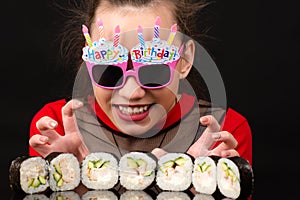 Funny young girl in birthday with sushi rolls