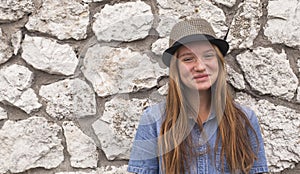 Funny young girl near a stone wall. Happy.