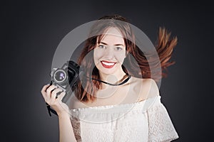 Funny young girl with photo camera with moving, blowing hair.