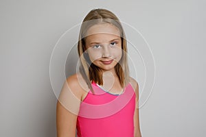 Funny young girl portrait. Little kid posing on light gray studio background