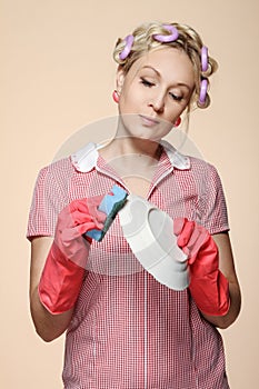 Funny young housewife with gloves holding scrubberr