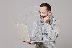 Funny young man in gray sweater, scarf isolated on grey background. Healthy lifestyle ill sick disease online treatment