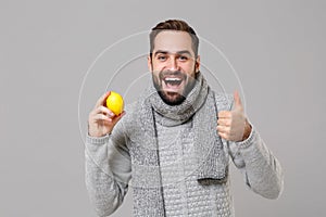 Funny young man in gray sweater, scarf posing isolated on grey background in studio. Healthy fashion lifestyle, people