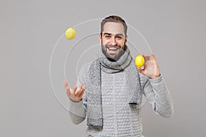 Funny young man in gray sweater, scarf posing isolated on grey wall background, studio portrait. Healthy fashion