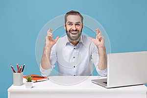 Funny young man in light shirt sit work at desk with pc laptop isolated on blue background. Achievement business career