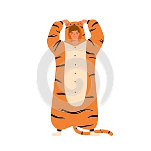 Funny young man wearing tiger kigurumi for pagama party. Male character standing in animal costume. Cheerful guy in cozy