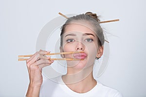 Funny young woman with chopsticks to roll in the mouth. Sexy lips with chopsticks.