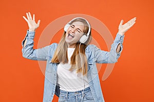 Funny young woman in denim clothes isolated on orange background. People lifestyle concept. Mock up copy space. Listen