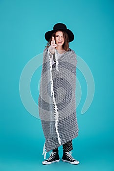 Funny young woman in hat covered in blanket