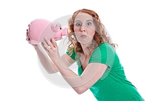 Funny: young woman holding piggy bank cuts grimace