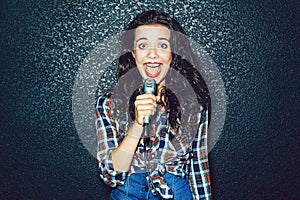 Funny young woman with microphone singing something