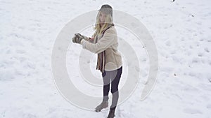 Funny young woman playing snow ball fight in winter. Girl snowballs game. Female in knit handmade hat and mittens with