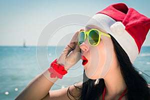 Funny young woman in Santa Claus hat and sunglasses