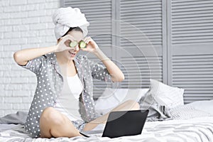 Funny young woman after shower using laptop. Skin care concept