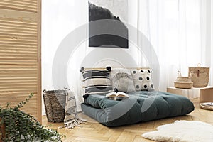 Green futon with pillows in boho bedroom interior with poster. Real photo photo