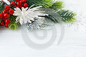 Fur-tree branches, red berries, decoration on white wood, top view, copy space