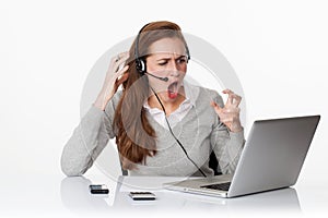 Furious 20s working woman under shock with headset and computer