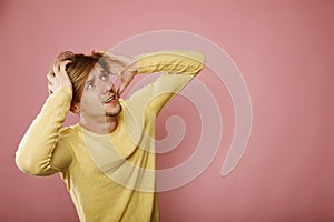 Furious angry mad man screaming looking up hold hand on head, young frustrated and stressed man isolated over pink background,