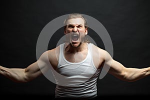 Furious bodybuilder wearing white singlet. man shouting his head off. photo