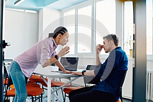 A furious business director of a startup office berating her employee for business mistakes and errors photo