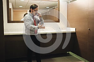 Furious Business Man Screaming On Cell Phone In Office Restroom