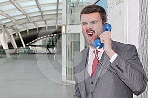 Furious businessman screaming on public phone