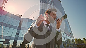 Furious businessman yelling smartphone loudspeaker at street sunlight close up