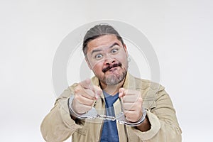 A furious man in handcuffs threatens his accuser or the policeman with legal action or harm.  on a white background photo