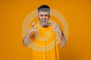 Furious man screaming and gesturing isolated over yellow background
