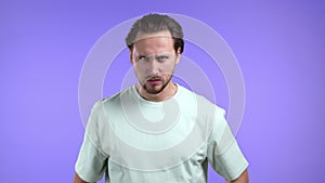 Furious man on violet background. European guy in stress and rage, he is in aggression and looking at camera with