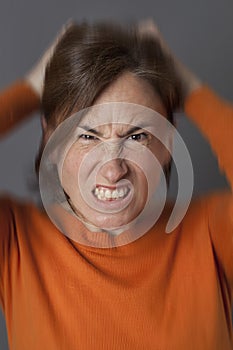 Furious middle aged woman pulling out her hair, blurred effects
