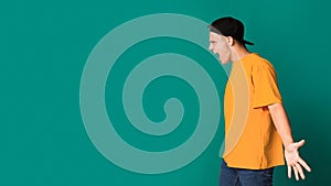 Furious teen guy shouting over turquoise background