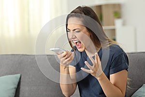 Furious woman shouting to smart phone at home